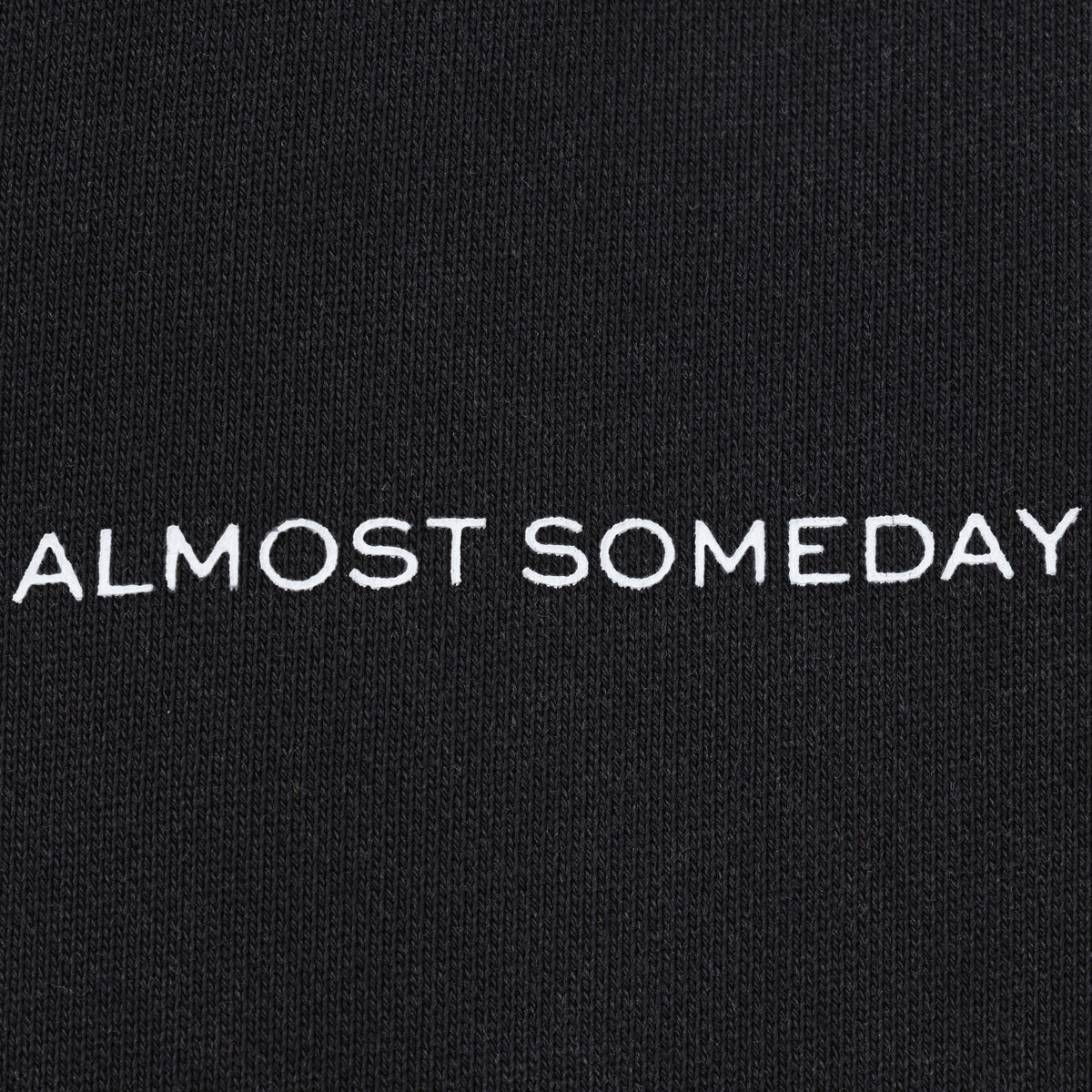 Smoke Flare Bottoms – Black – Close-up of white Almost Someday thigh lettering on black knit fabric