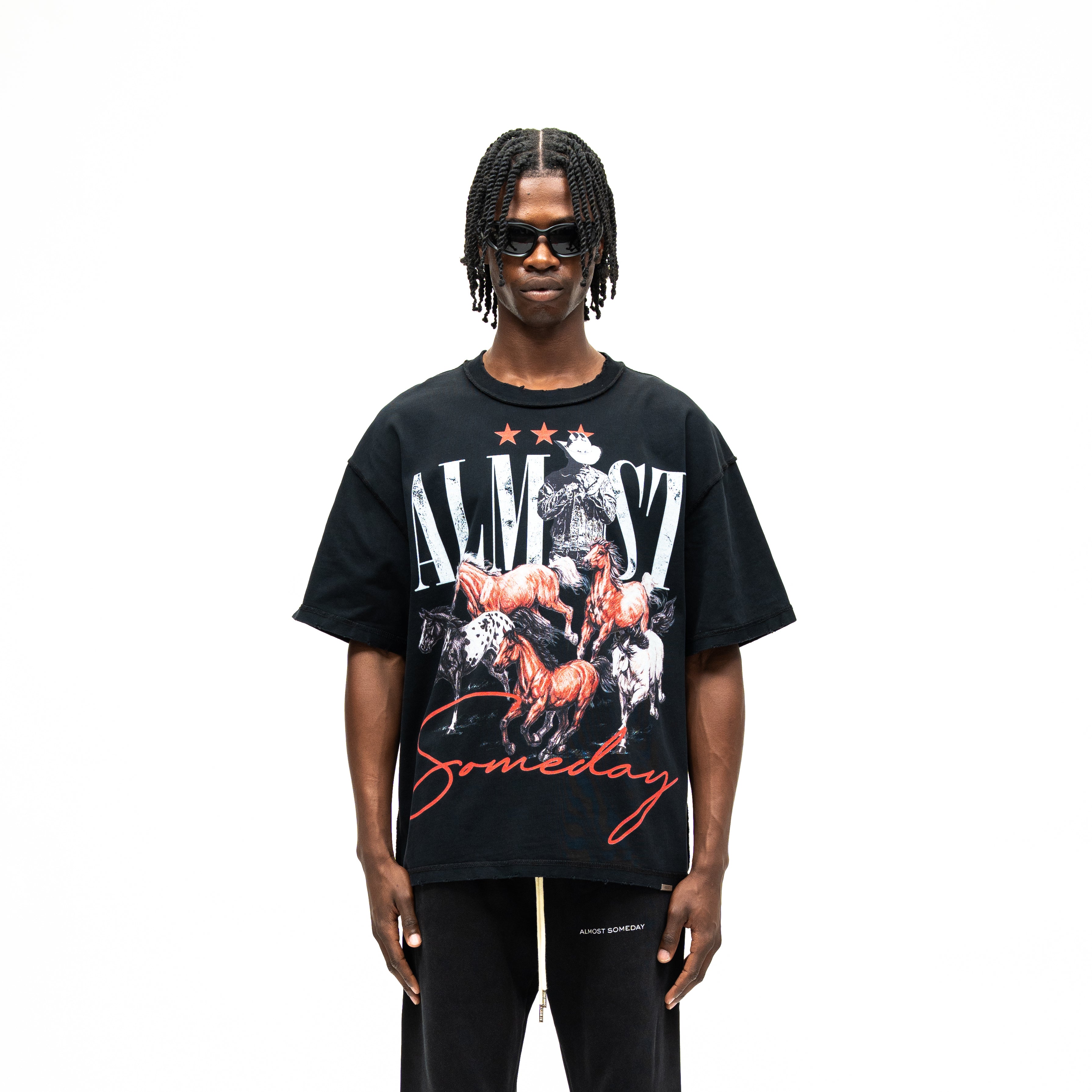 Smoke Tee – Black – Front view on model showing cowboy and running horses graphic with white Almost lettering and red Someday script