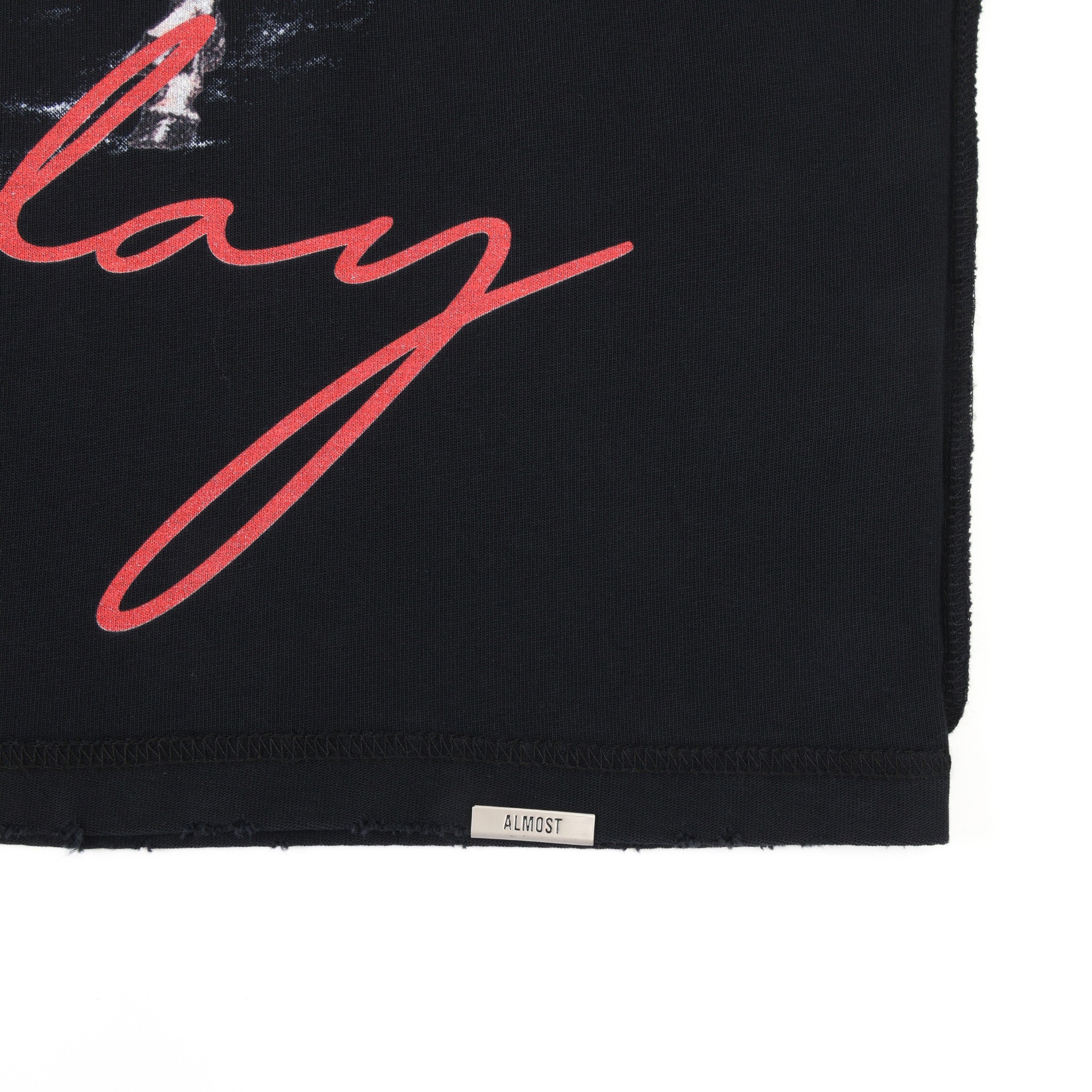 Smoke Tee – Black – Close-up of lower hem with Almost label and red script detail