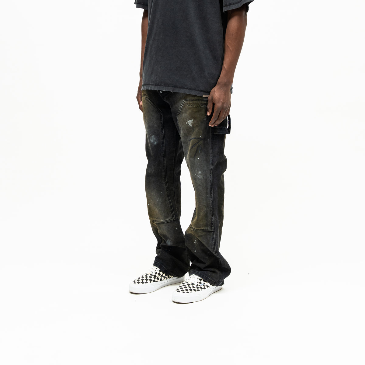 Spade Pants – Black – Three-quarter front view on model showing paneled legs, paint splatters, and side utility loop